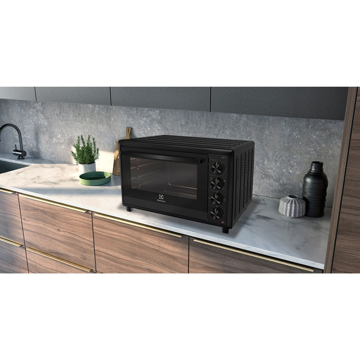 Electrolux EOT5622XFG UltimateTaste 700 freestanding electric oven, 56 L, in black, shown on a marble kitchen countertop against a grey stone splashback